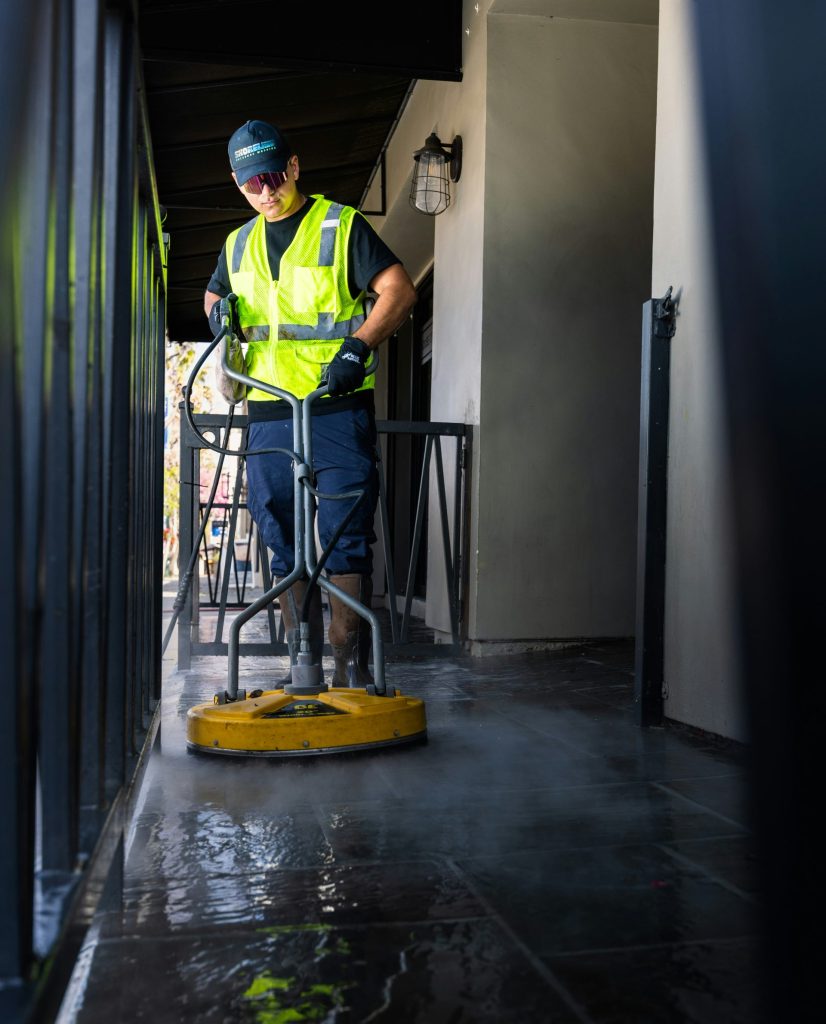 a man in a yellow vest is cleaning the floor