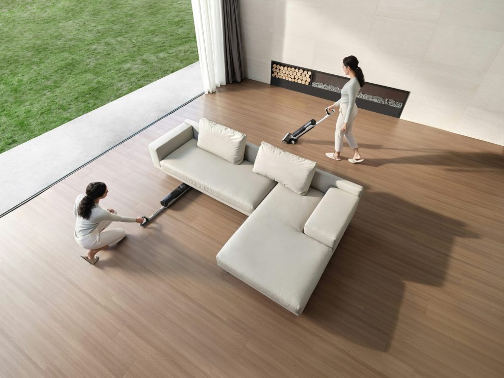 Two women cleaning a modern living room with vacuum cleaners.